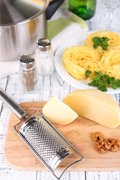 Composition with tasty spaghetti, grater, cheese, on wooden table background — Stock Photo, Image