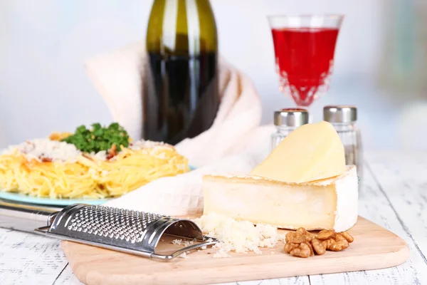 Složení s chutné špagety, sýr, láhev vína a skla na dřevěný stůl, na světlé pozadí — Stock fotografie