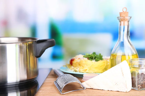 Makarna hazırlama işlemi. pan, rende, peynir, parlak zemin üzerine ahşap tablo içinde satır spagetti ile kompozisyon — Stok fotoğraf