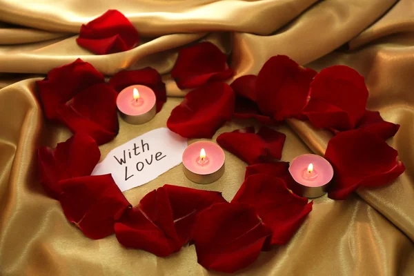 Beautiful red rose petals with candles and greeting card, close up — Stock Photo, Image