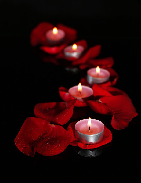 Красивые лепестки роз со свечами, на темном фоне
