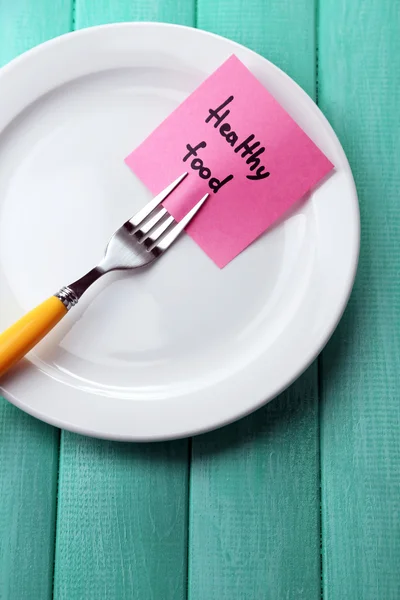 Nota carta con messaggio attaccato alla forchetta, su piatto, su fondo di legno — Foto Stock