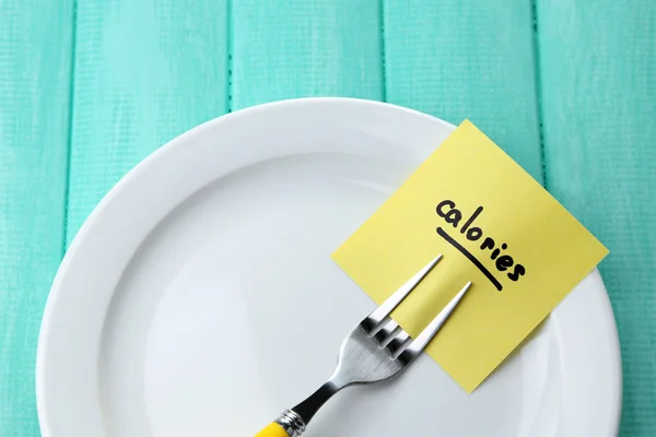 Note paper with message  attached to fork, on plate, on wooden background — Stock Photo, Image