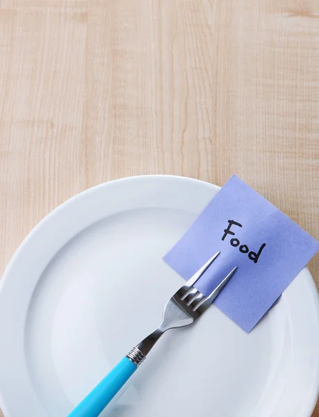 Note paper with message  attached to fork, on plate, on color wooden background — Stock Photo, Image