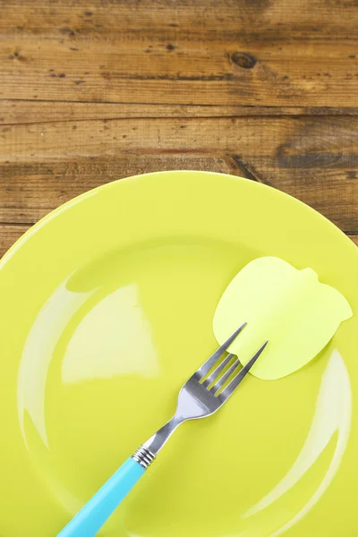 Empty note paper attached to fork, on plate, on color wooden background — Stock Photo, Image