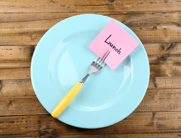 Note paper with message  attached to fork, on plate, on wooden background — Stock Photo, Image