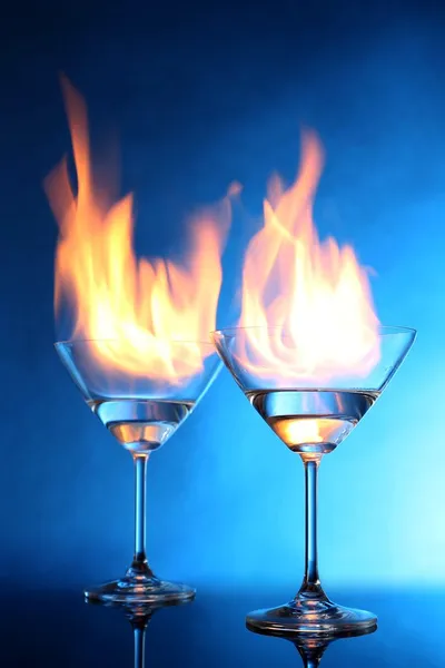 Glasses with burning alcohol on blue background Royalty Free Stock Images