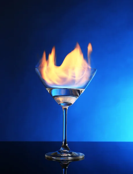 Glass with burning alcohol on blue background Stock Picture