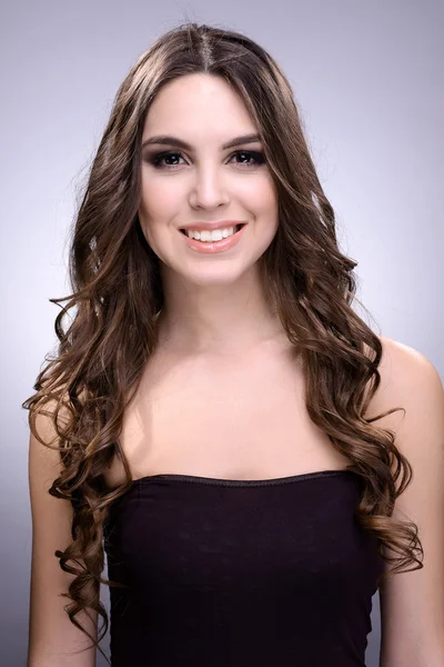 Hermosa joven con el pelo largo sobre fondo gris Imágenes de stock libres de derechos