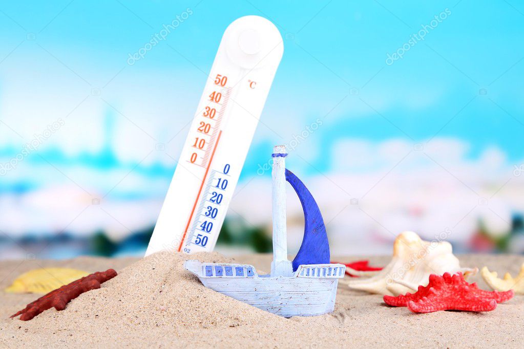 Thermometer  in sand on bright background