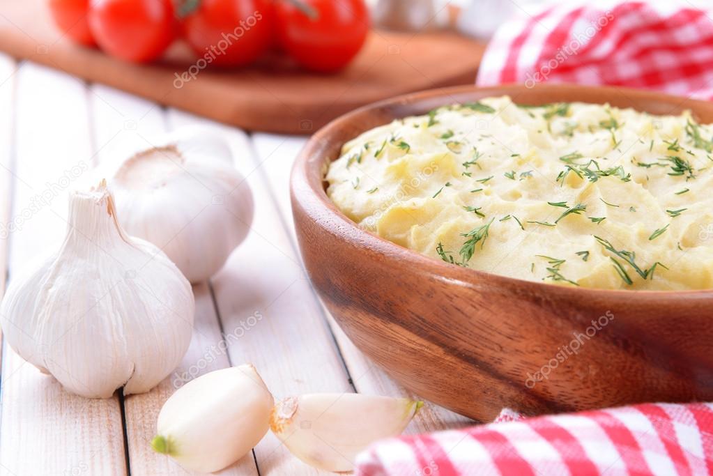 Delicious mashed potatoes with greens in bowl on table close-up