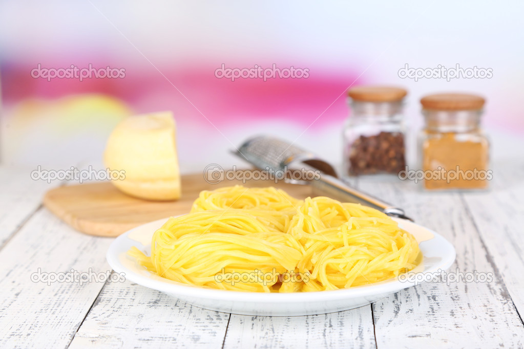 Composition with tasty spaghetti, grater, cheese, and spices on wooden table, on light background