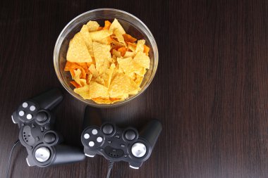 siyah oyun denetleyicileri ve aperatifler ahşap arka plan üzerine bir kase