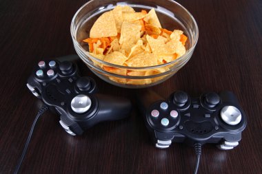 siyah oyun denetleyicileri ve aperatifler ahşap arka plan üzerine bir kase