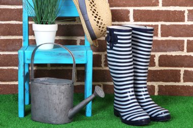 Çift renkli gumboots, şapka, sandalye ve sulama olabilir renkli duvar arka plan üzerinde çim üzerinde