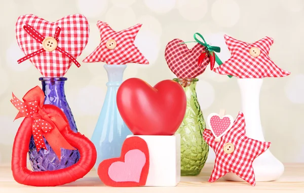 Hand-made textile hearts in different vases on wooden table, on light background — Stock Photo, Image