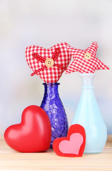 Handgefertigte Textilherzen in verschiedenen Vasen auf Holztisch, auf hellem Hintergrund — Stockfoto