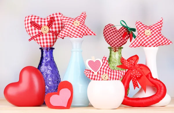 Coeurs textiles faits à la main dans différents vases sur table en bois, sur fond clair — Photo