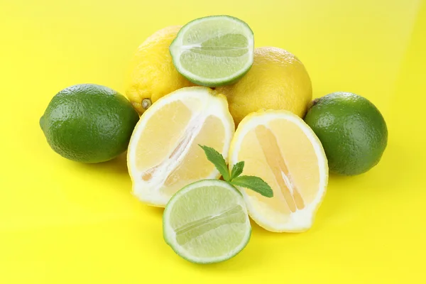 Limones y limas, sobre fondo amarillo — Foto de Stock