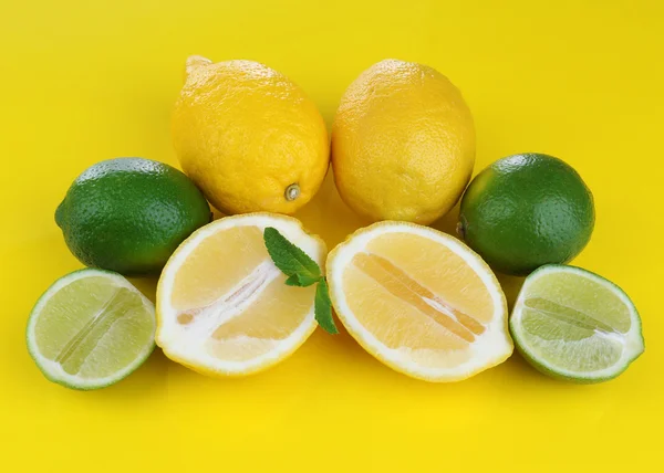 Lemons and limes, on yellow background — Stock Photo, Image