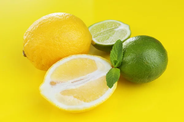 Limoni e lime, su fondo giallo — Foto Stock