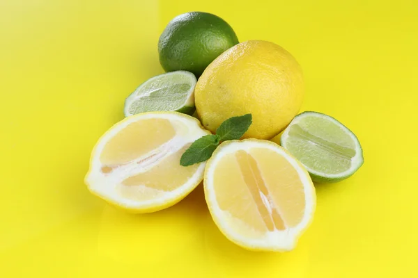 Lemons and limes, on yellow background — Stock Photo, Image