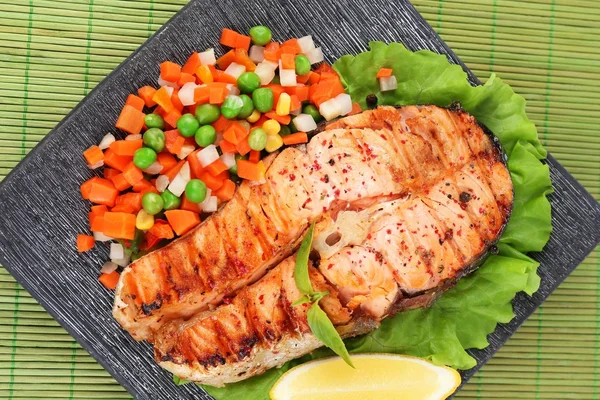 Salmão grelhado saboroso com legumes, em esteira de bambu — Fotografia de Stock