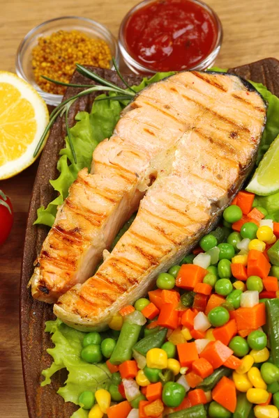 Tasty grilled salmon with vegetables, on wooden table — Stock Photo, Image
