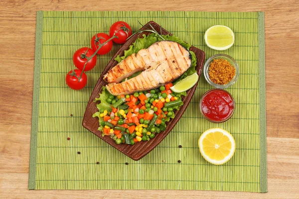 Tasty grilled salmon with vegetables, on bamboo mat — Stock Photo, Image