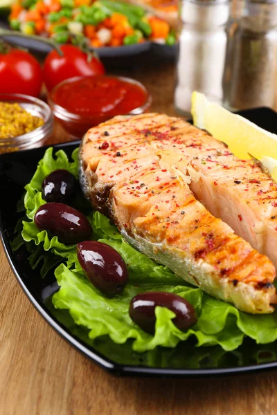 Gustoso salmone grigliato con limone e verdure, su tavola di legno — Foto Stock