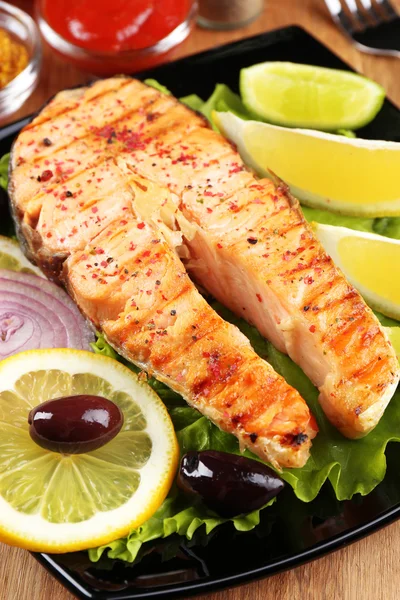 Salmão grelhado saboroso com limão e legumes, na mesa de madeira — Fotografia de Stock