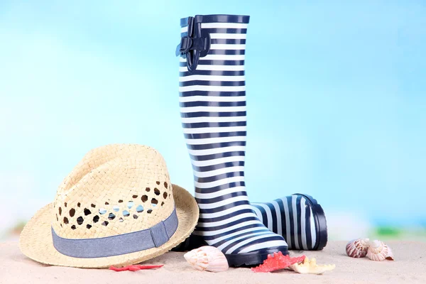 Par de botas de goma de colores y sombrero sobre fondo brillante — Foto de Stock