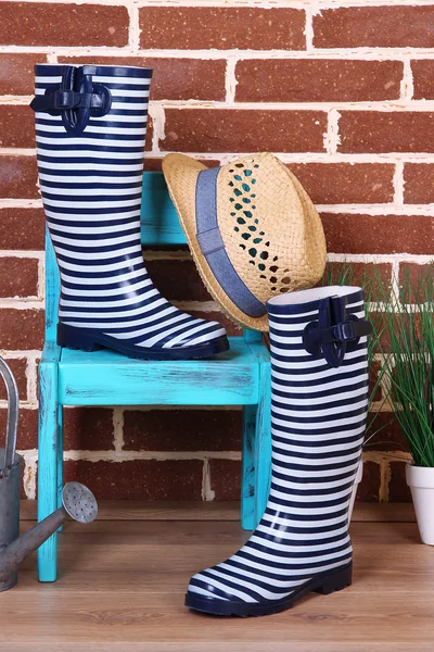 植物の鍋、椅子、壁の背景の色に水まき缶でカラフルなゴム長靴のペア — ストック写真