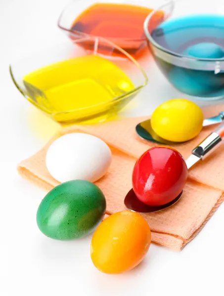 Cuencos con pintura para huevos de Pascua y huevos, aislados en blanco — Foto de Stock