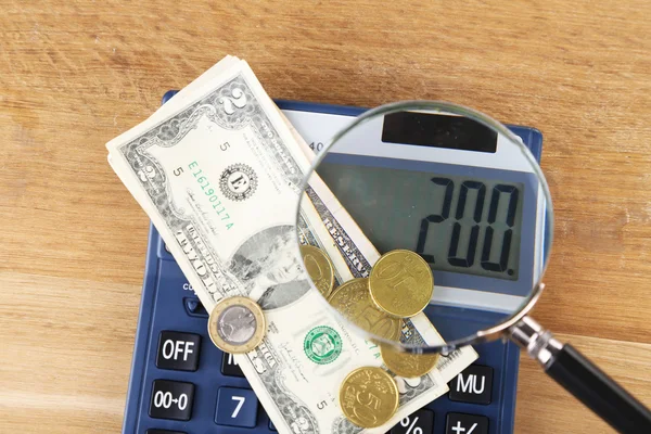 Conceito de fraude com lupa e calculadora, sobre fundo de madeira — Fotografia de Stock