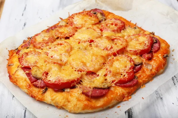 Pizza fatta in casa su carta da forno da vicino — Foto Stock