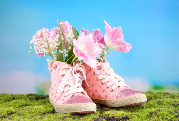 Hermosos zapatos de goma con flores en el interior sobre hierba verde, sobre fondo brillante —  Fotos de Stock