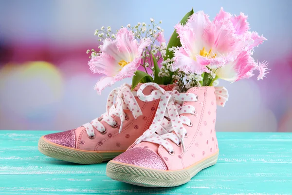 Beautiful gumshoes with flowers inside on wooden table, on bright background — Stock Photo, Image