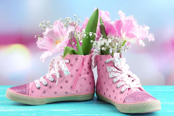 Mooie gumshoes met bloemen binnen op houten tafel, op lichte achtergrond — Stockfoto