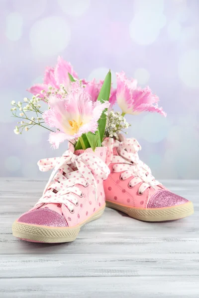 Hermosos zapatos de goma con flores en el interior en la mesa de madera, sobre fondo claro —  Fotos de Stock