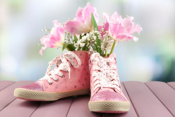 Mooie gumshoes met bloemen binnen op houten tafel, op lichte achtergrond — Stockfoto