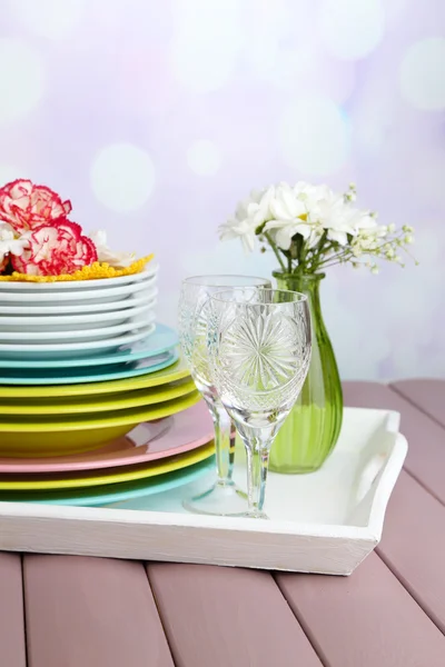 Pilha de pratos e flores de cerâmica colorida, na bandeja, na mesa de madeira, no fundo claro — Fotografia de Stock