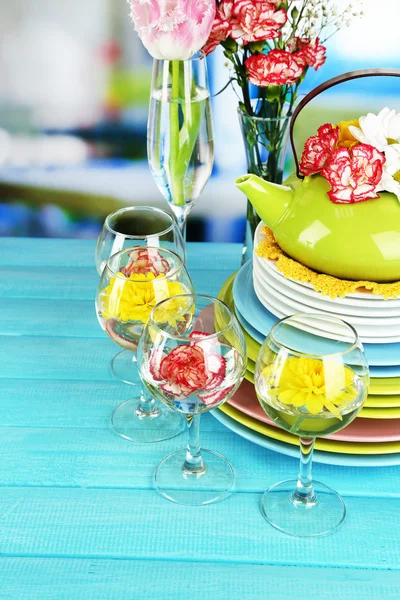 Renkli seramik yemekleri ve üzerinde açık renkli ahşap bir masaya çiçek yığını — Stok fotoğraf