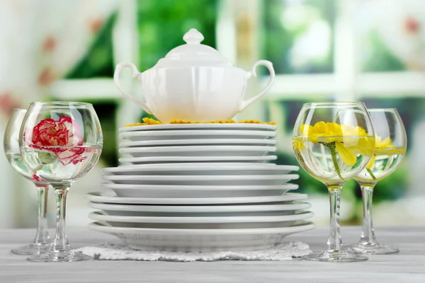 Stapel van kleurrijke keramische gerechten en bloemen, op het dienblad, op houten tafel, op lichte achtergrond — Stockfoto
