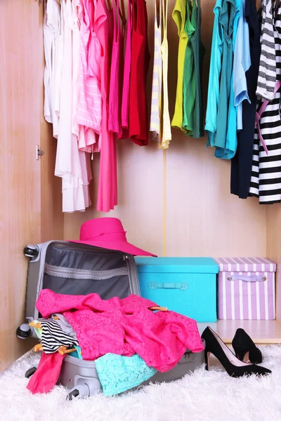 Roupa feminina em guarda-roupa e mala no quarto — Fotografia de Stock