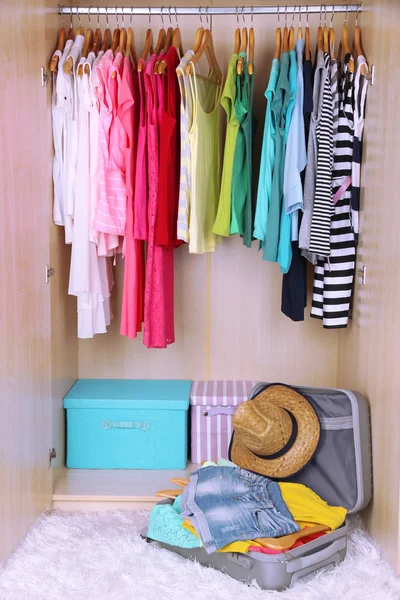 Female clothes in wardrobe and suitcase in room — Stock Photo, Image