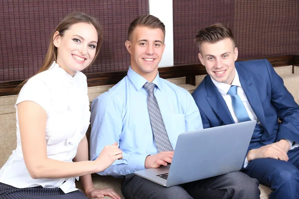 Young business people sitting on couch in office — Stock Photo, Image