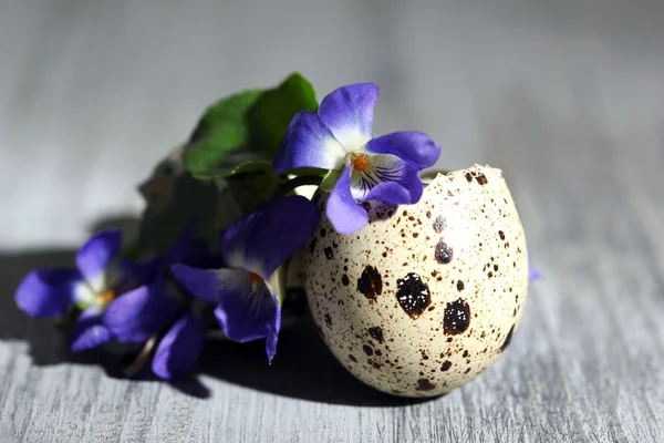 复活节组成与紫罗兰花在蛋壳木制的桌子上 — 图库照片