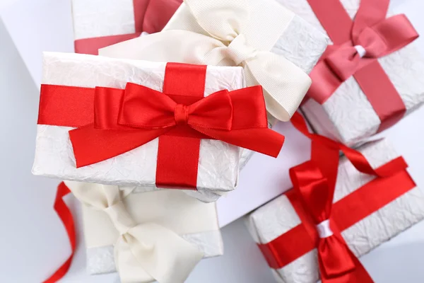 Beautiful gifts with red ribbons, close up — Stock Photo, Image