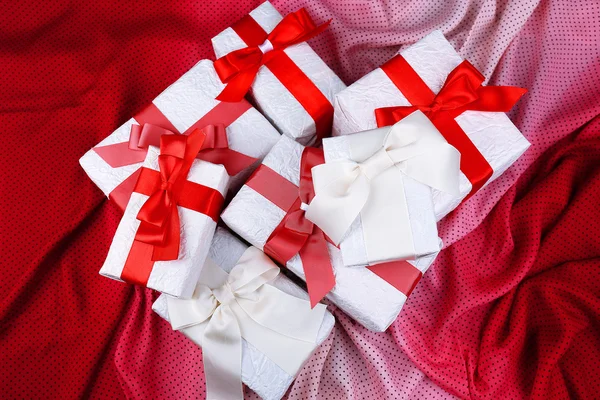 Hermosos regalos con cintas rojas en tela rosa — Foto de Stock